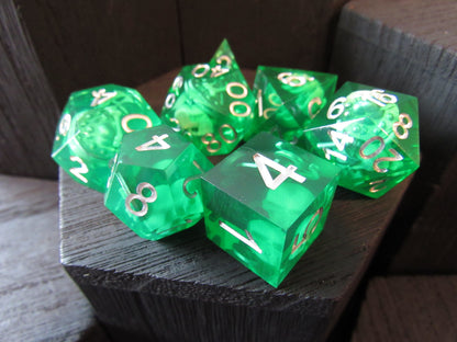 Set of green dice with gold numbers on a wooden surface gelatinous cube