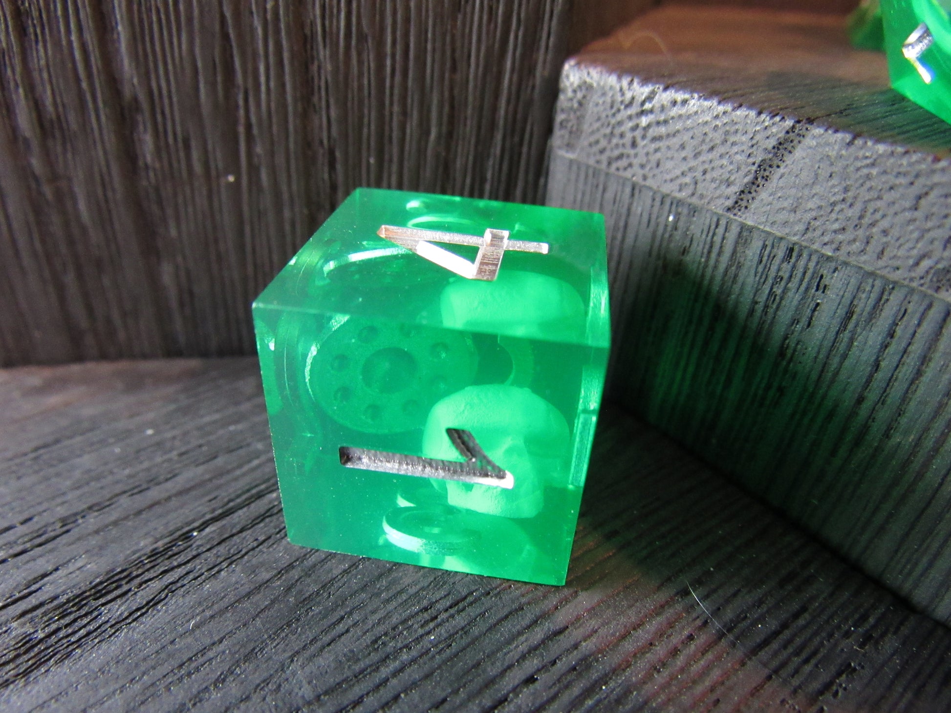 Green transparent cube with a number '4' on a wooden surface gelatinous cube dice
