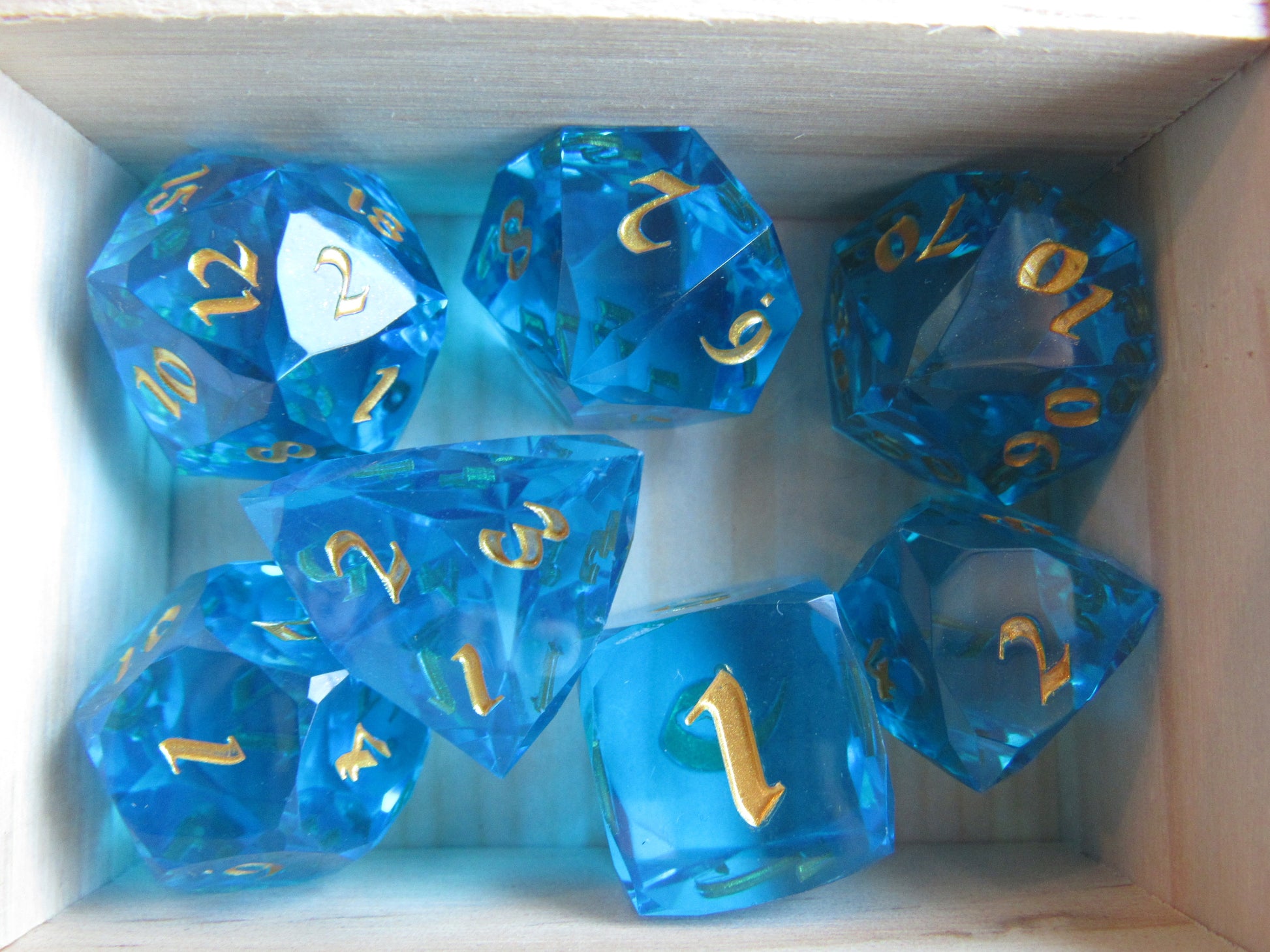 Set of blue polyhedral dice with gold numbers in a box gem gemstone cut faceted resin dice