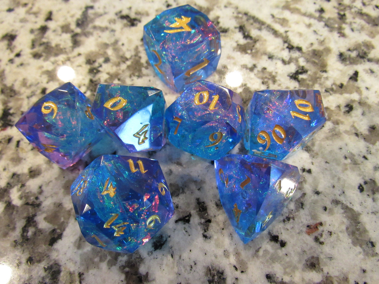Set of blue and purple dice with gold numbers on a marble surface gem gemstone cut faceted resin dice