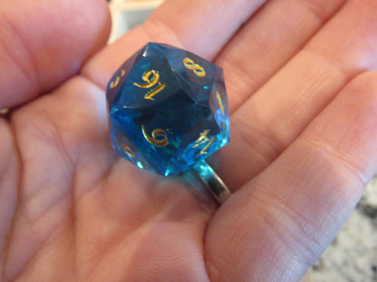 Blue polyhedral dice with gold numbers held in a hand gem gemstone cut faceted resin dice