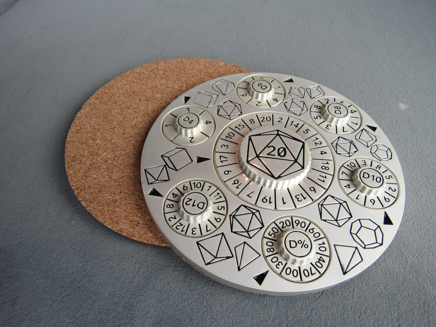 Circular metal die with d20 design on a gray surface dungeons and dragons dice