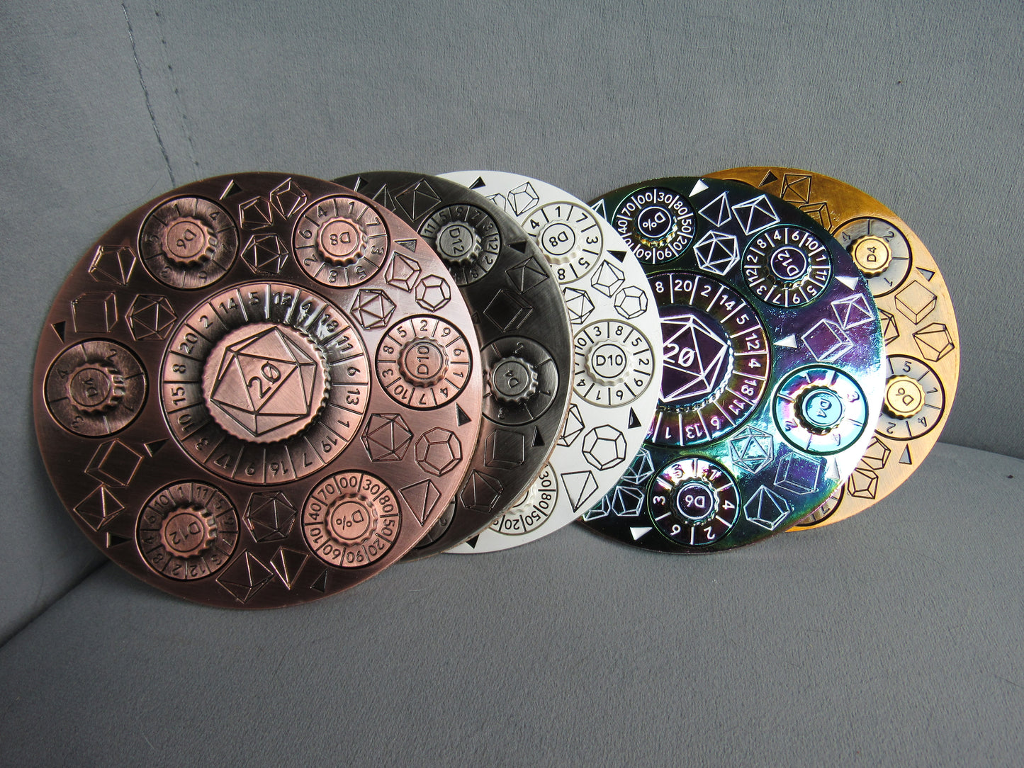 Set of five circular metal objects with embossed designs on a gray background dungeons and dragons spinner dice