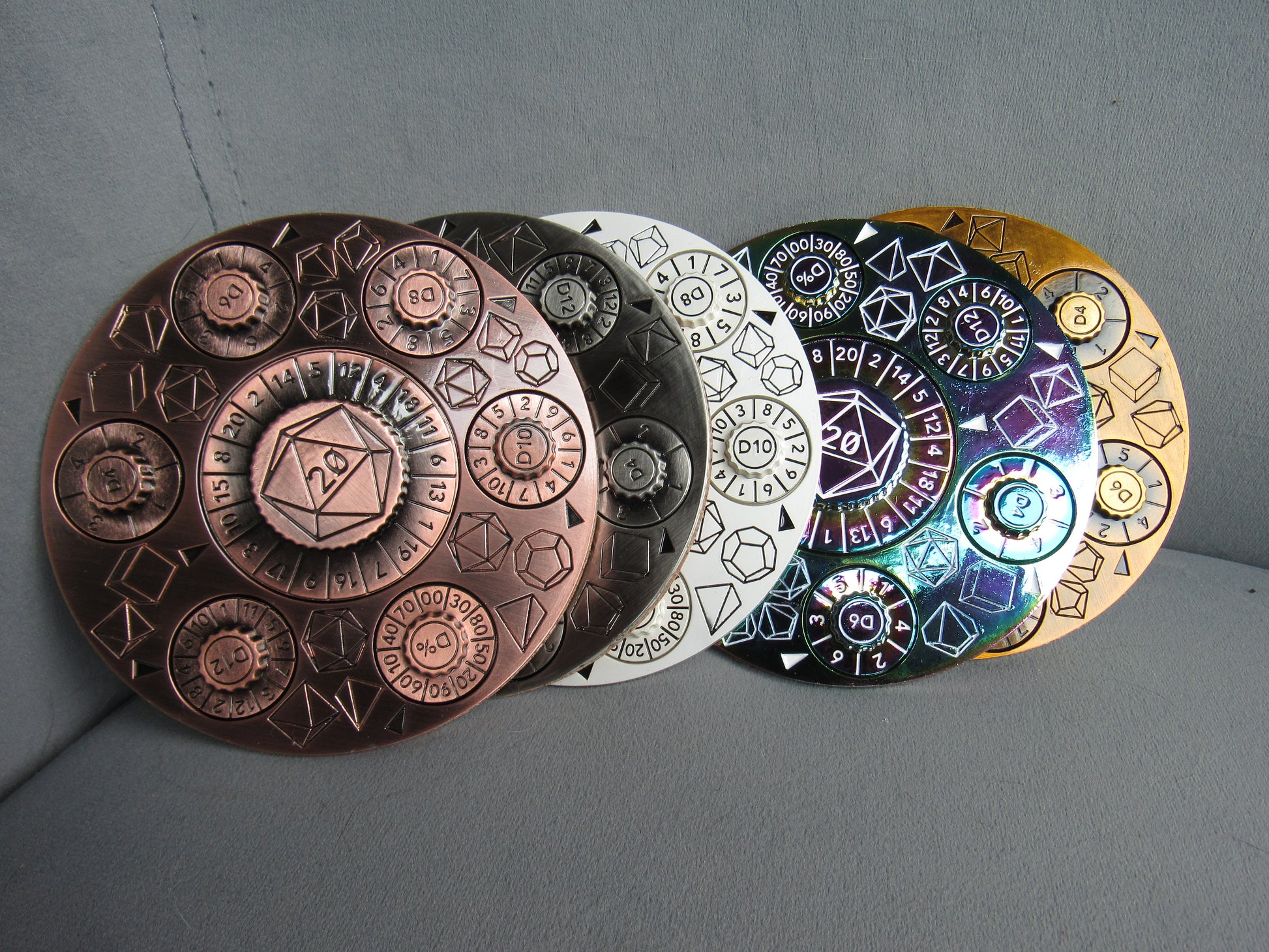 Set of five circular metal objects with embossed designs on a gray background dungeons and dragons spinner dice